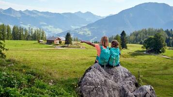 Two people sitting on a rock with a mountainous landscape in the background.