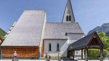 A church with a steeple, a wooden structure, and a paved area.