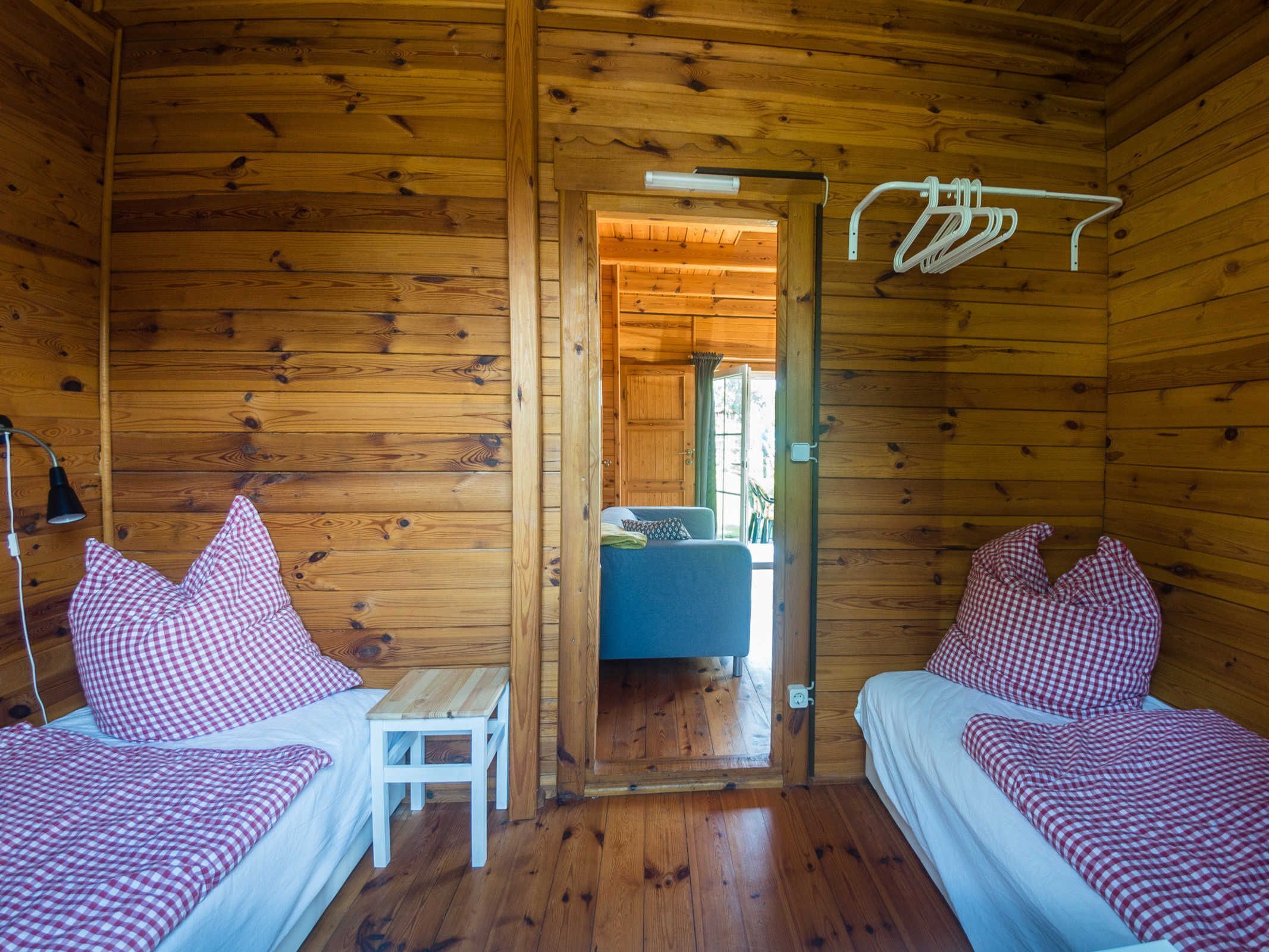 A cabin with two beds, a small table, and a hanging clothes rack.
