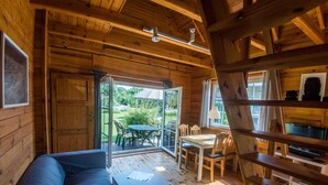 A cozy cabin interior with a wooden interior, a sofa, a table, and a TV. - House 2 - SCHMIDT'S Cottages in the countryside (Lüdershagen)