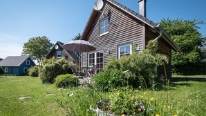 A wooden house with a satellite dish, a chimney, and a garden with flowers and plants. - House 10 - SCHMIDT`S cottages in the countryside (Lüdershagen)