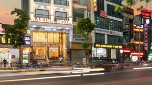 A hotel with a prominent sign, multiple floors, and a street view with vehicles and storefronts.