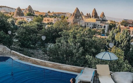 A swimming pool with a person relaxing, surrounded by lounge chairs and a view of unique rock formations.