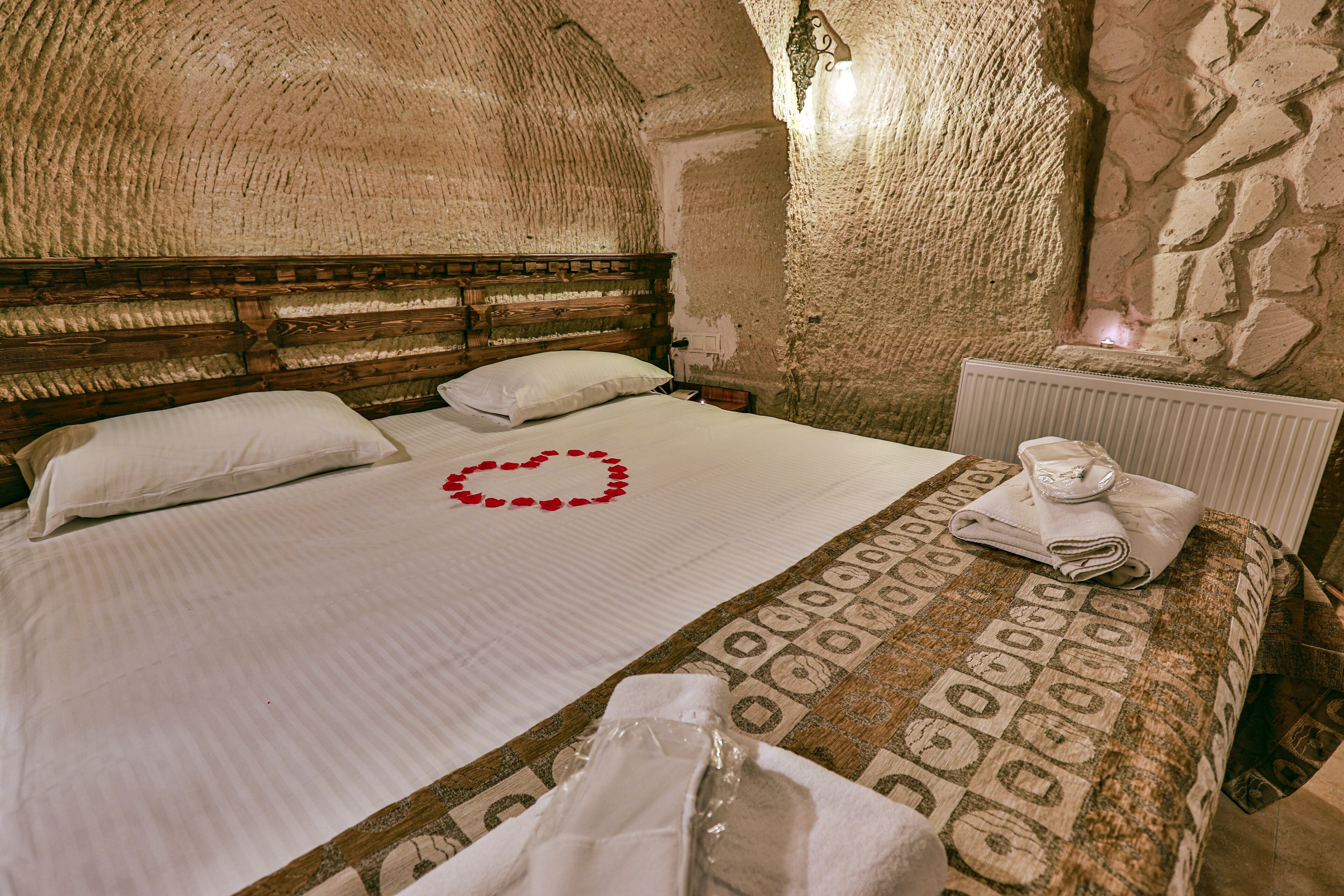 A bed with a heart-shaped decoration, a wooden headboard, and a patterned bedspread.