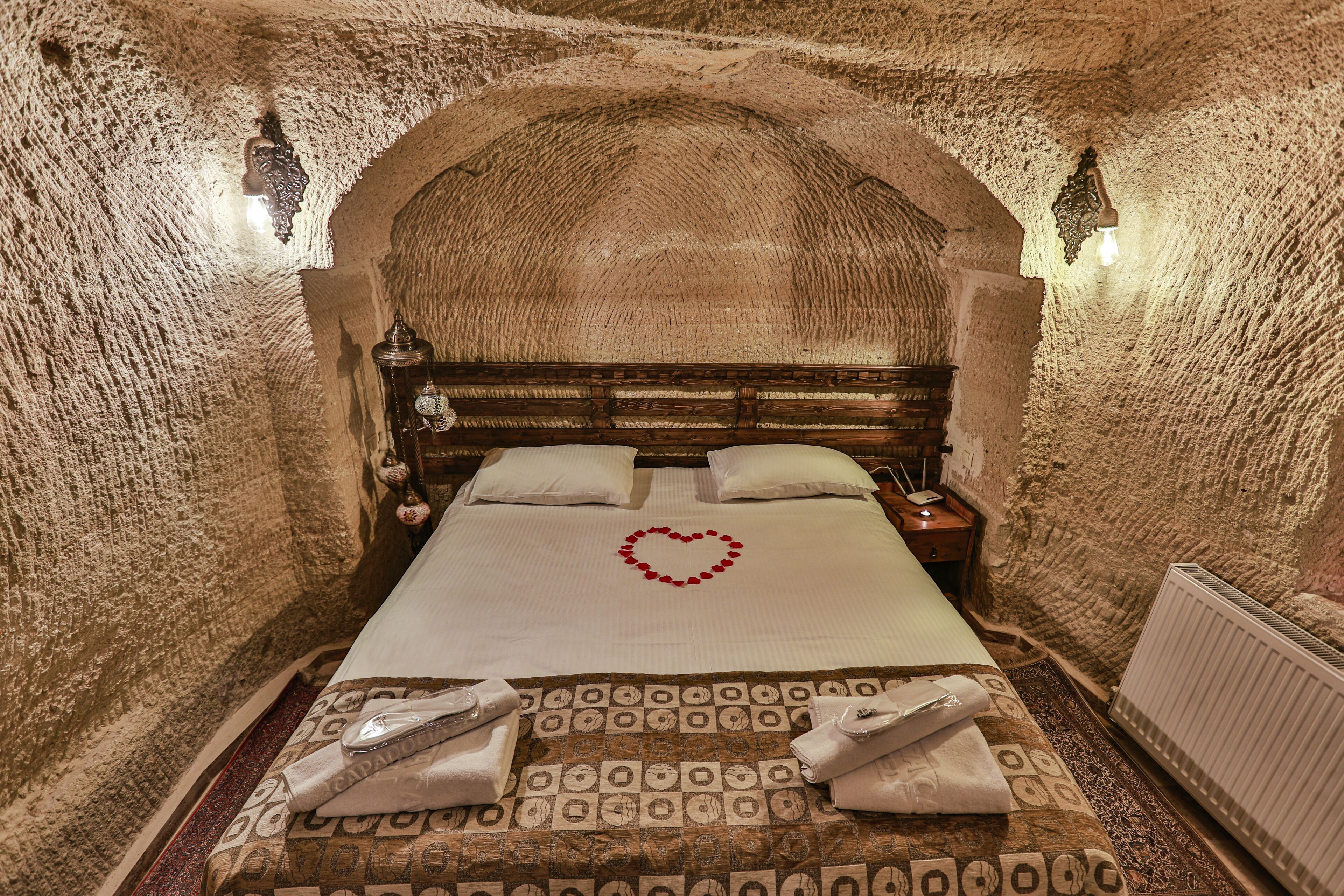 A room with a bed, a heart-shaped decoration on the bed, and towels on the floor.