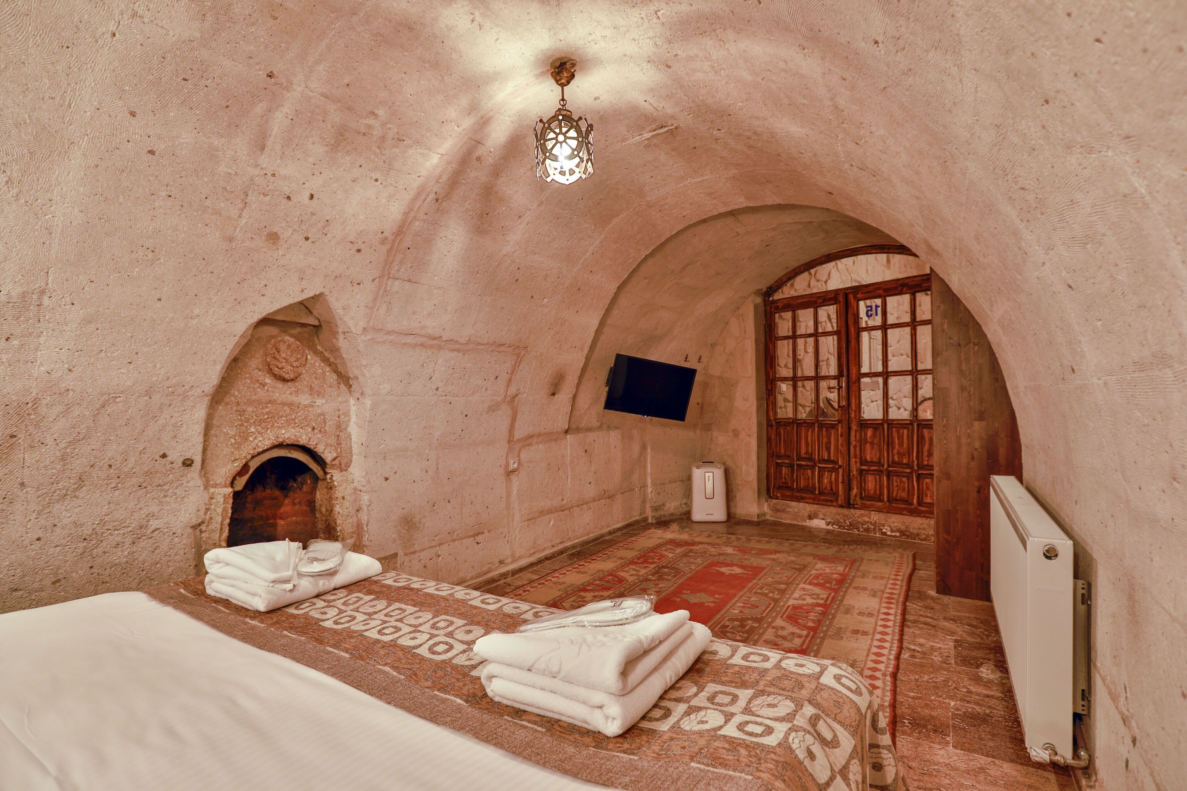 A room with a bed, a fireplace, a television, and a radiator.