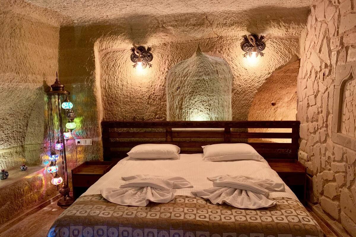 A room with a bed, a nightstand, and a wall-mounted lamp.