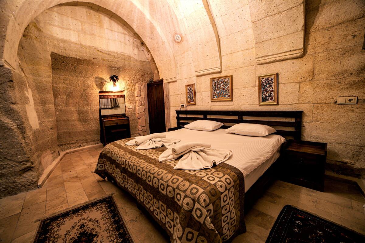 A room with a bed, a nightstand, a lamp, and a patterned rug.
