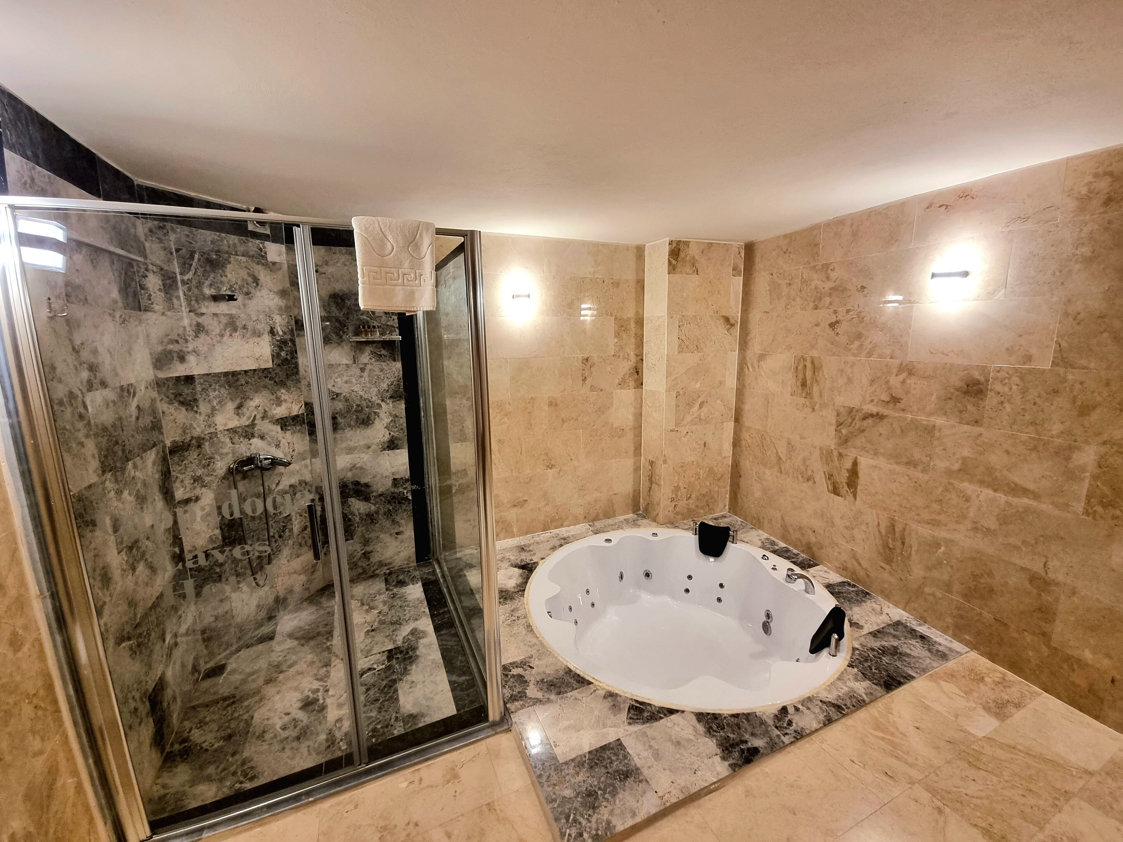 A modern bathroom with a glass-enclosed shower, a freestanding bathtub, and marble flooring.