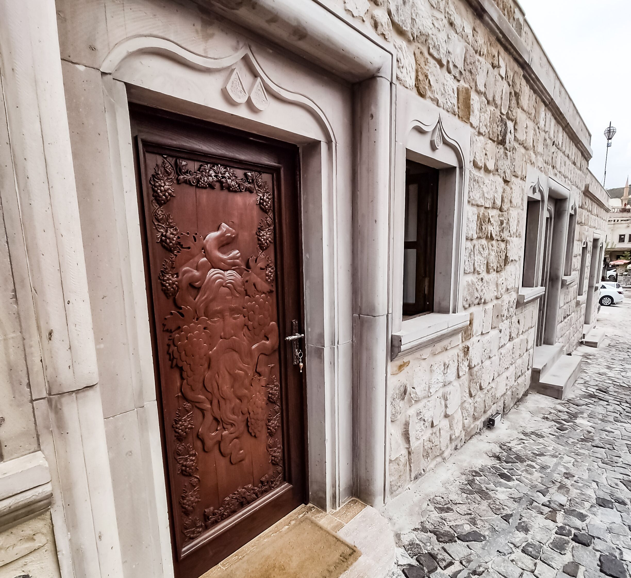 A historic building with a detailed wooden door, stone walls, and a cobblestone street.