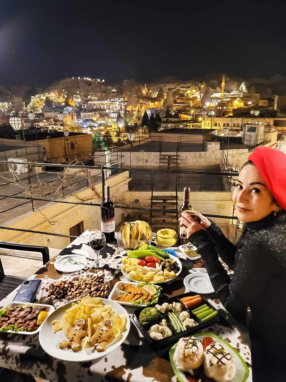 A rooftop dining area with a table set for a meal, various dishes, and a bottle of wine.