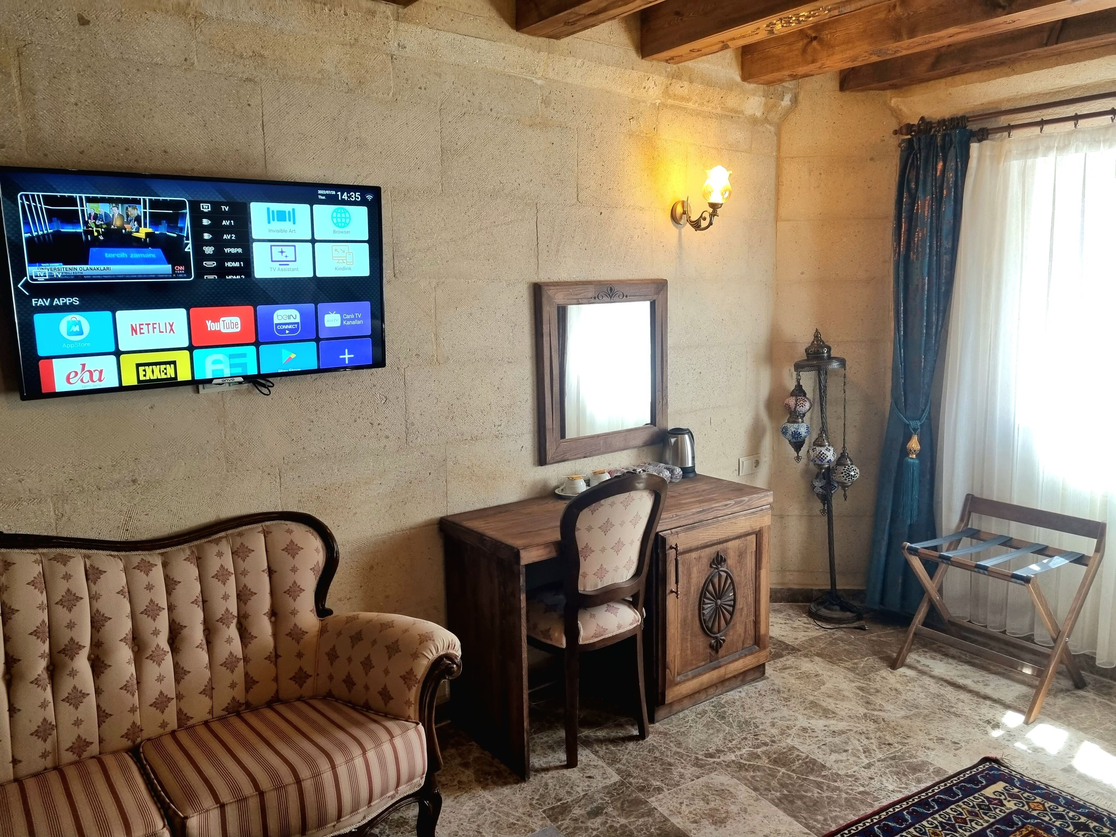 Un salón acogedor con una televisión montada en la pared, un mueble de madera, un sofá con cojines y una lámpara decorativa.