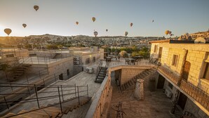 A rooftop terrace with a view of a town and hot air balloons in the distance. - Cappadocia Caves Hotel (Nevsehir)