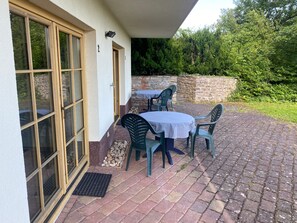 En uteplats med ett bord och stolar, en stenmur och en dörr med glaspaneler.