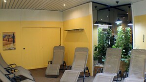 Ein Zimmer mit vier Liegesesseln, einer Tür, einem Gemälde und einer Topfpflanze.