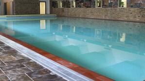 Ein Innenpool mit gefliestem Boden und Wänden, die mit Kunstwerken verziert sind.