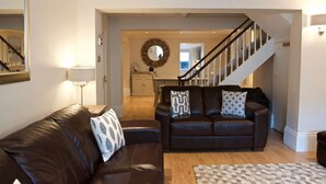 A living room with two dark brown leather sofas, a patterned rug, and a staircase leading to another room. - Malvern House - coastal townhouse located in the heart of Deal (Deal)