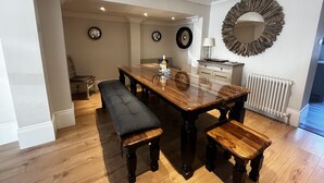 A dining area with a wooden table and benches, a mirror, and a radiator. - Malvern House - coastal townhouse located in the heart of Deal (Deal)