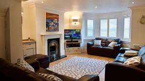 A living room with a fireplace, a television, and a sofa. - Malvern House - coastal townhouse located in the heart of Deal (Deal)