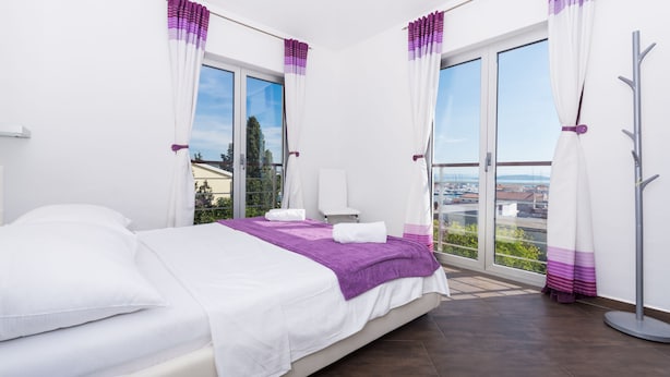 Ein Schlafzimmer mit Bett, Fenster und Blick auf die Stadt.