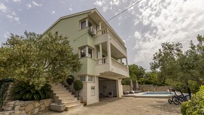 Edifici de dues plantes amb un balcó, una piscina i una bicicleta aparcada a l'exterior.