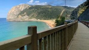 A wooden boardwalk along a coastal area with a view of a beach and a large cliff. - Bekozu Apartment, Urresti (Gautegiz Arteaga)