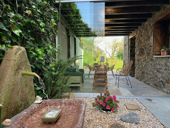 A stone wall, a water feature, and a seating area with chairs and a table.