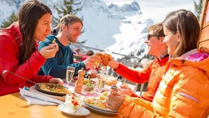 A group of people dining outdoors with a mountain backdrop.