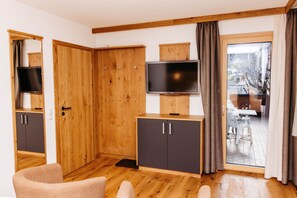 Una habitación con armarios de madera, televisor y puerta corrediza de vidrio que da a un espacio exterior.