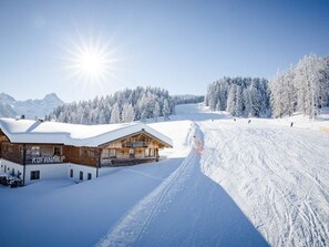 A snow-covered mountain landscape with a wooden building labeled 'RUFANALP' and a ski slope.