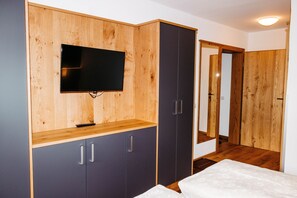 Un dormitorio con una cama, un televisor montado en un mueble de madera y un armario.