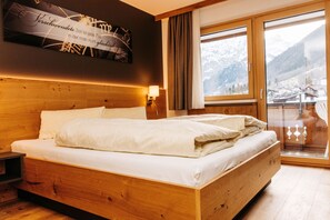 Una cama de madera en una habitación con vistas a las montañas a través de un ventanal grande.
