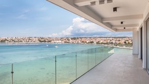 A balcony with a glass railing overlooking a coastal cityscape. - Hotel Kaneo (Novalja)