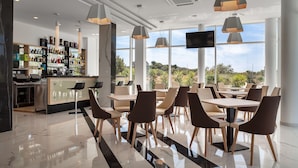 A modern restaurant with a bar area, large windows, and a view of the outdoors. - Hotel Kaneo (Novalja)