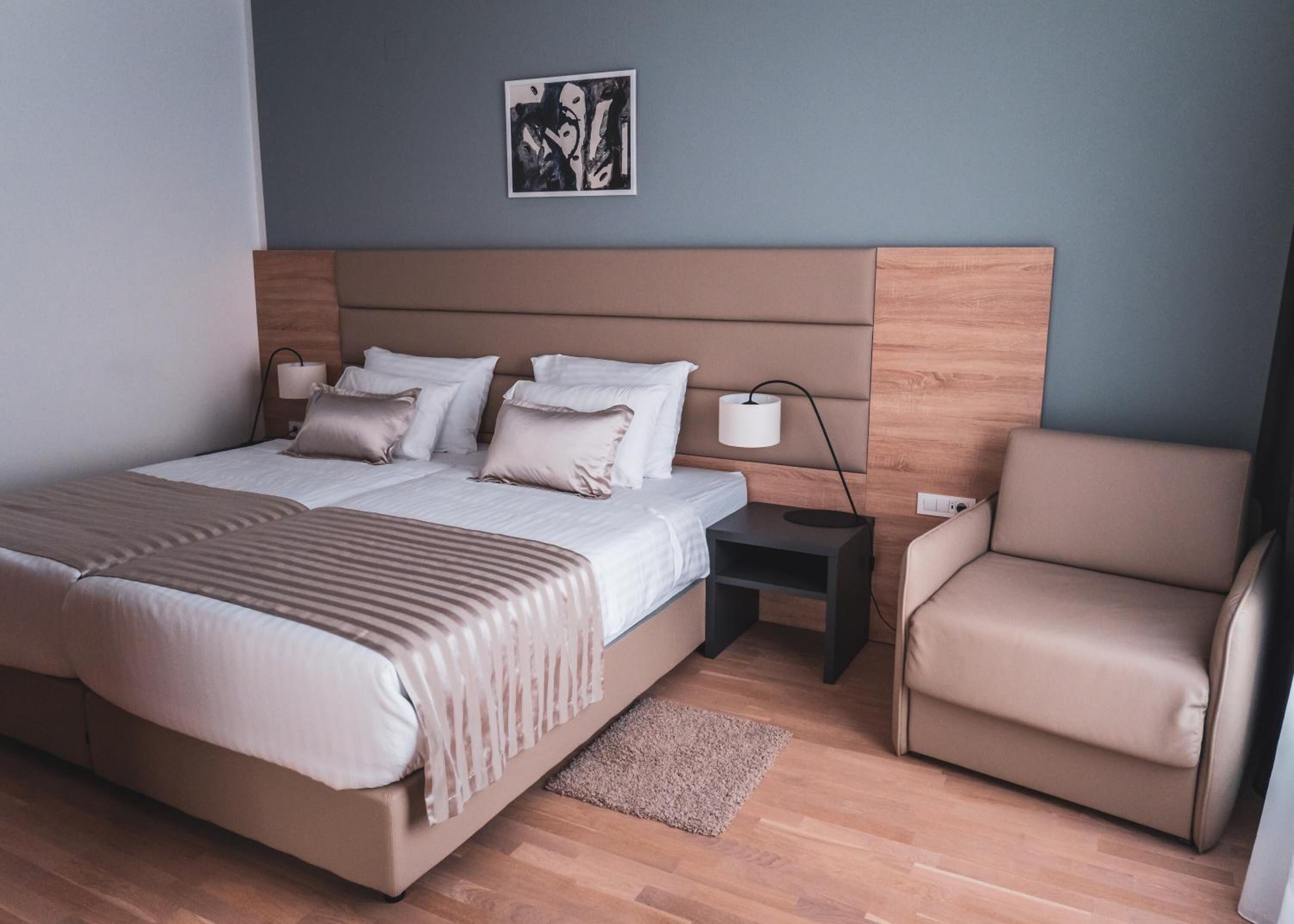 A modern bedroom with a large bed, bedside tables, a chair, and a wall art piece.