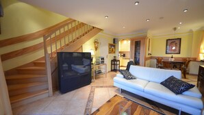 Ein geräumiger Wohnbereich mit Treppe, einem weißen Sofa und einem Essbereich.