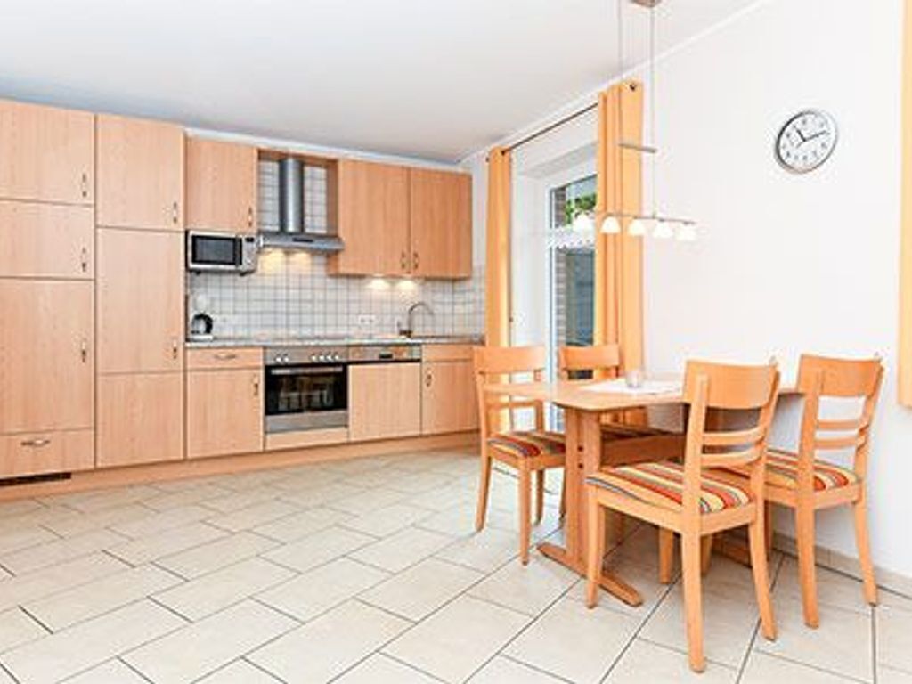 Et moderne køkken med træskabe, en mikrobølgeovn og et spiseområde med et bord og stole.