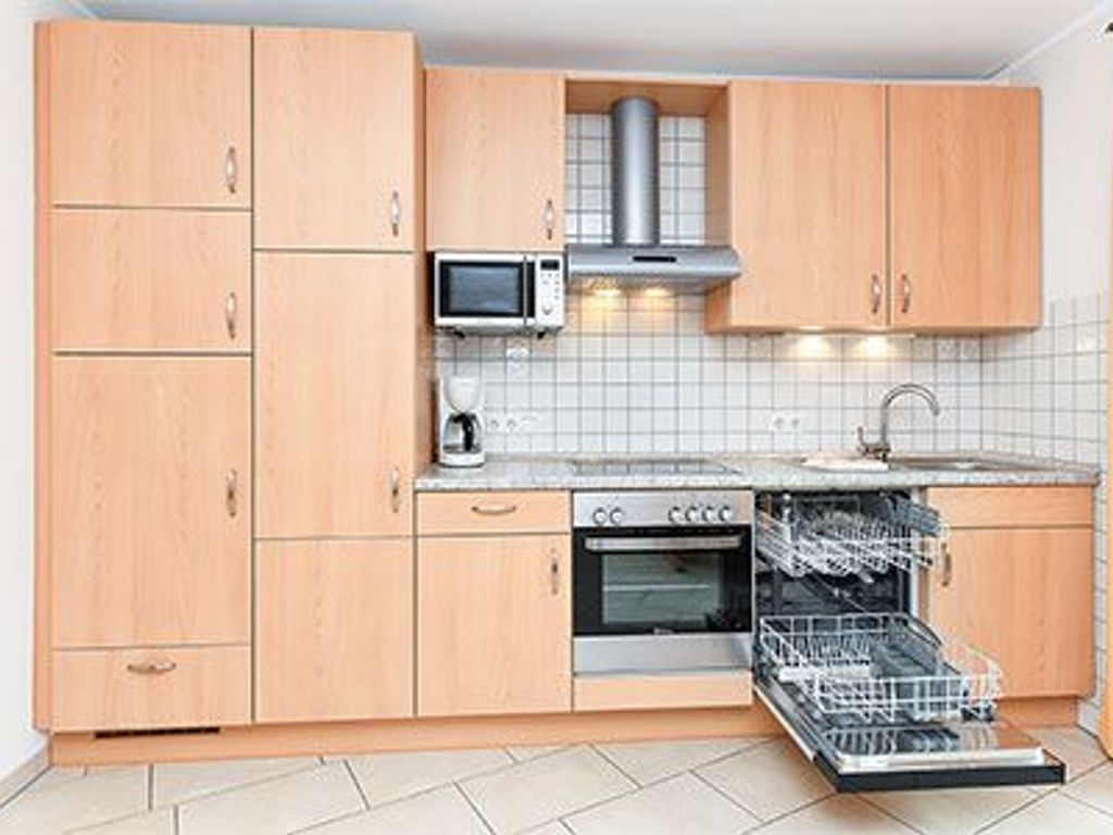 Une cuisine avec des meubles de rangement en bois, un four à micro-ondes, une cuisinière et un lave-vaisselle.