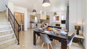 Une cuisine moderne avec un coin repas, un escalier et un salon.