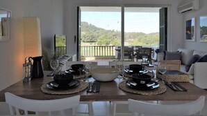 Ein Essbereich mit einem großen Tisch für vier Personen, Blick ins Freie und modernem Interieur.