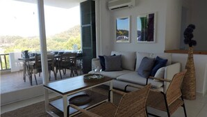 Ein modernes Wohnzimmer mit einer Couch, Sesseln, einem Couchtisch und einem Essbereich mit Tisch und Stühlen.