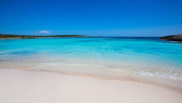 Ein Strand mit klarem türkisblauem Wasser und weißem Sand.