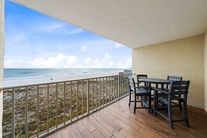 A balcony with a view of the beach, wooden flooring, and a table with chairs. - Seacrest 305- You Deserve a Beach Break! Book Today (Gulf Shores)