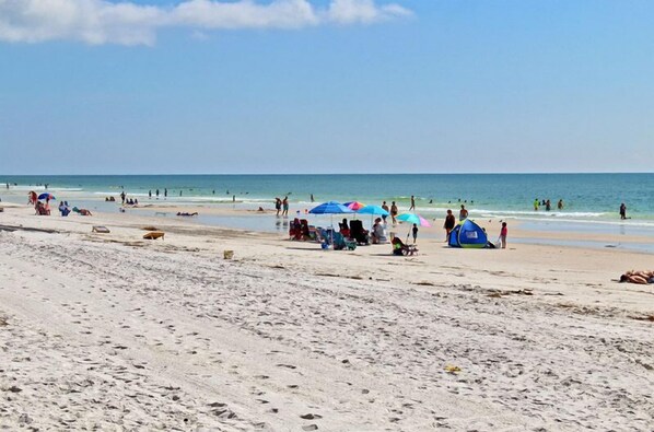 Ein Strand mit Menschen, Sonnenschirmen und einem Zelt.
