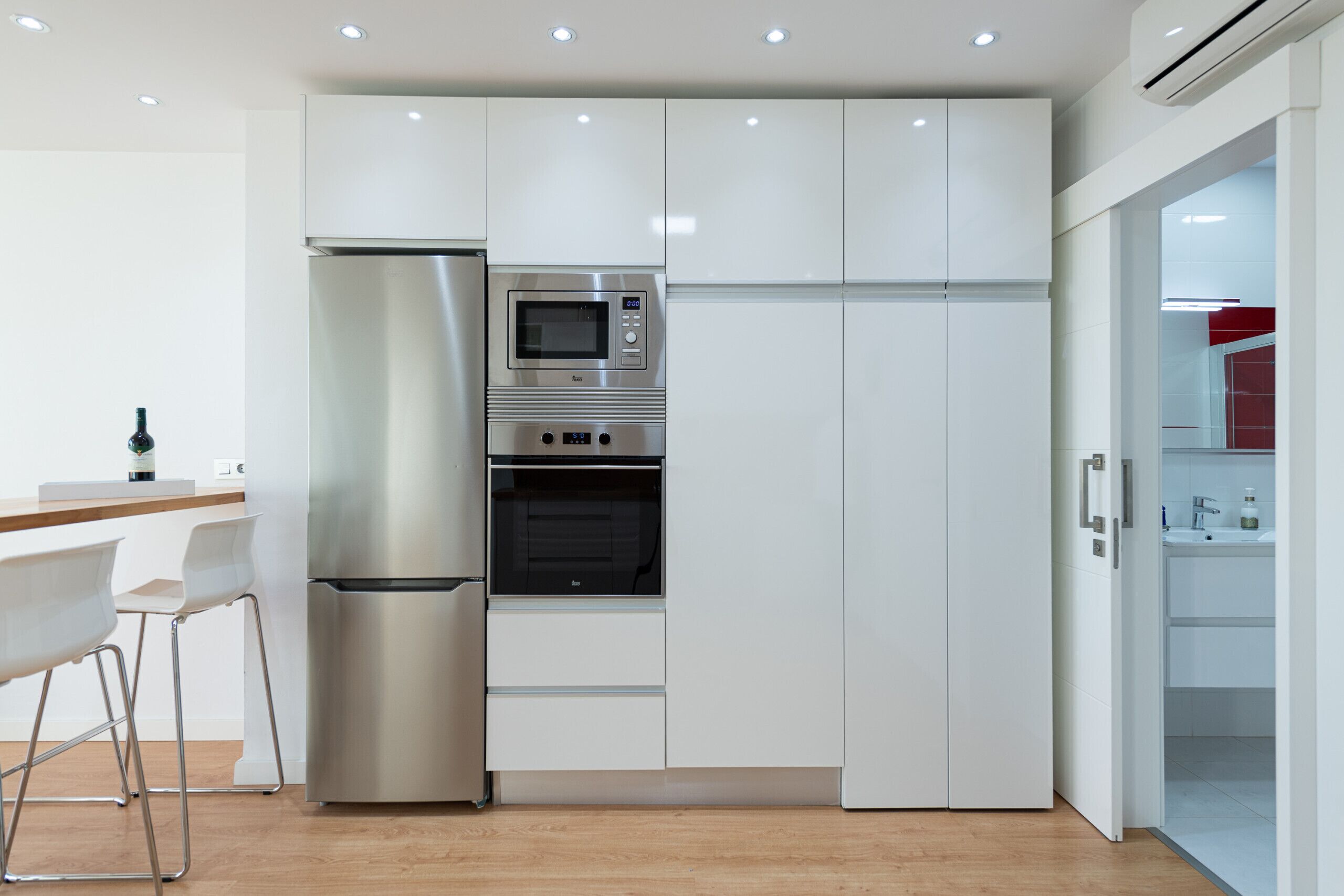 A modern kitchen with stainless steel appliances, white cabinetry, and a wooden countertop.