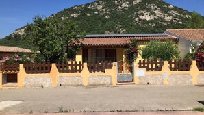 Ein Gebäude mit einem Ziegeldach, einem Holzzaun und einem Berg im Hintergrund.