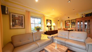 Una sala de estar con dos sofás color beige, una mesa de centro de madera y una mesa de comedor con sillas.