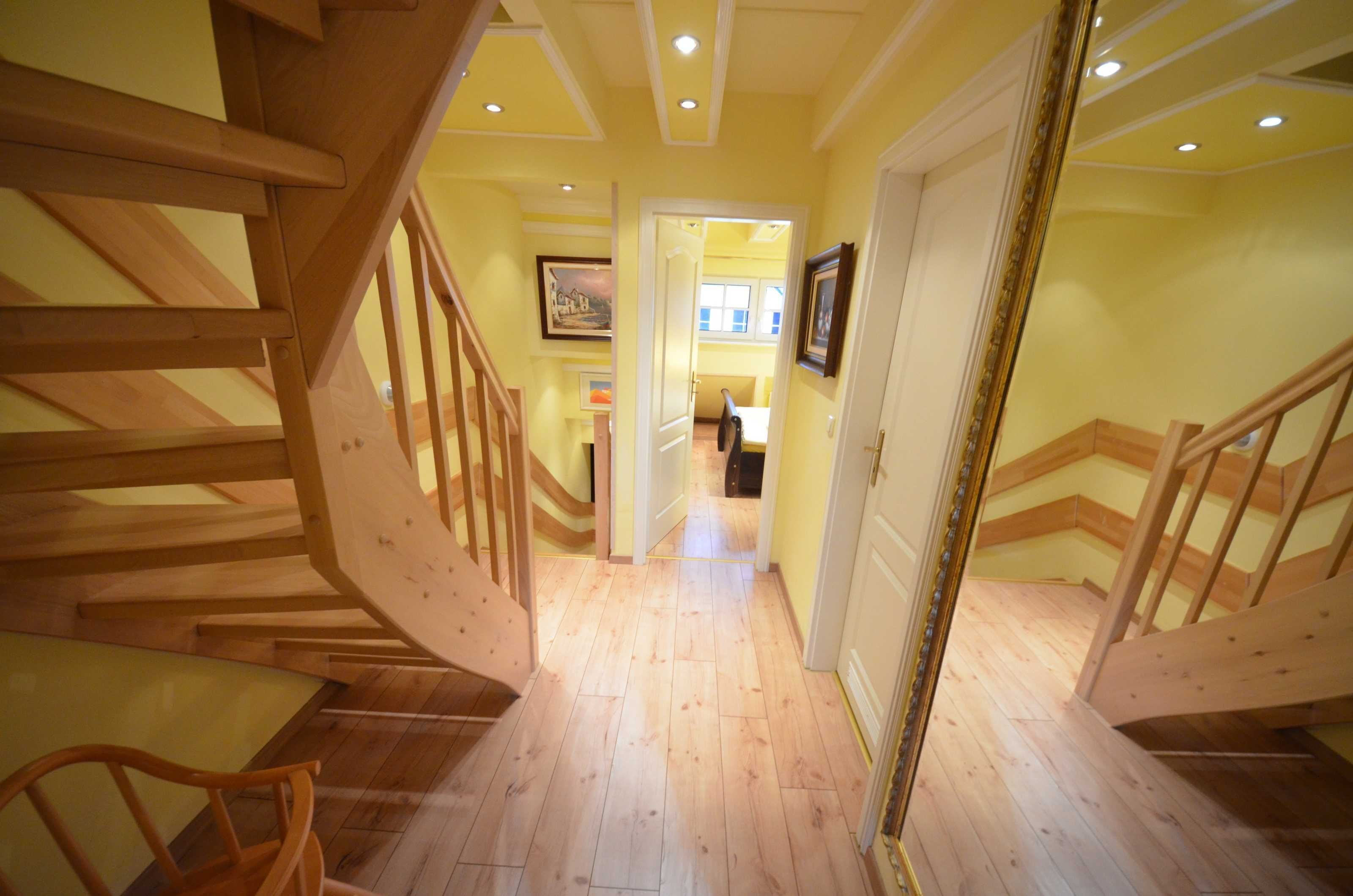 A wooden staircase leading to a room with a wooden floor and a door with a gold frame.