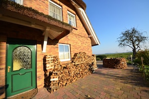 Ein Haus aus Backsteinen mit einer grünen Tür, einem Fenster und einem strohgedeckten Dach.