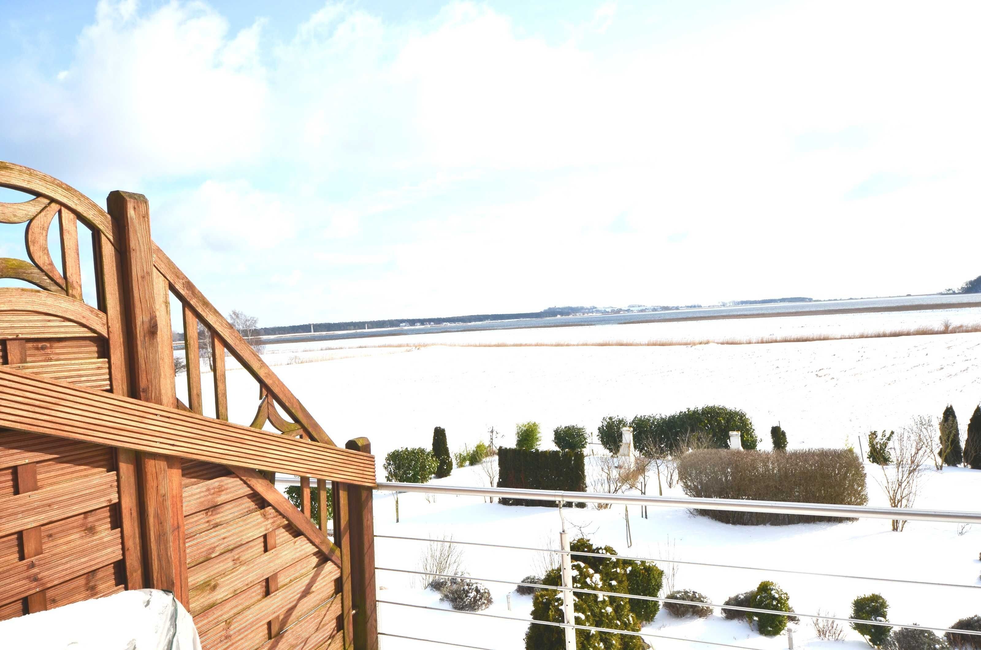 Une terrasse en bois offrant une vue sur un paysage enneigé et des arbres au loin.